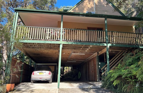 Patonga House | Treetops retreat - pole house set against a sandstone rock face in the tree tops