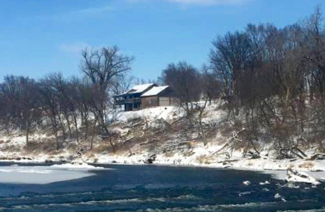Cabin on bluff of Big Sioux River with rushing waters of the Klondike Dam below.