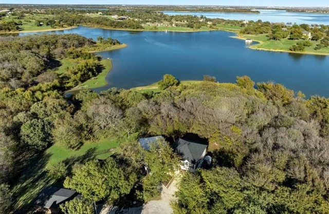 Lakefront retreat just steps from Lake Lewisville! Enjoy 341 ft of shoreline, a private cove, sandy beach, fire pit, and pergola with built-in grill. Inside: lake views, travertine floors, cozy fireplace, and an upstairs game room with balcony.