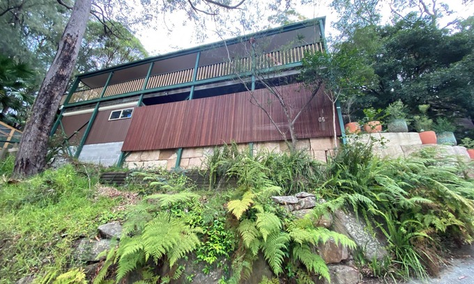 Patonga House | Treetops retreat - pole house set against a sandstone rock face in the tree tops